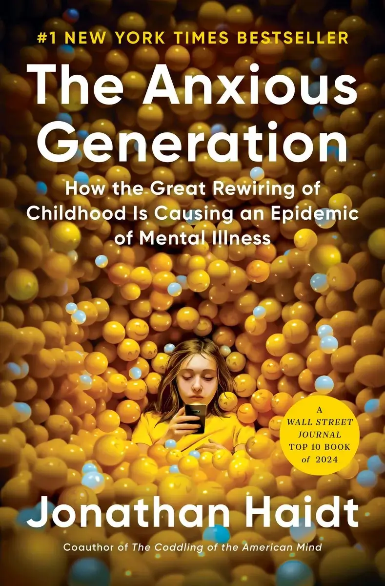 Image depicts book cover for The Anxious Generation by Jonathan Haidt. A girl sits surrounded by yellow balls, frowning and looking at her smartphone.